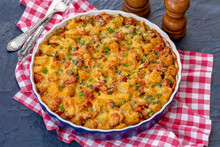 Potato Casserole With Sausages, Onion, Tomato And Cheese. Baking Dish With Tasty Potato Casserole On Dark Background.