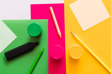 Wall Mural - top view of stationery near jars with paint on colorful background.