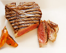 Partially Sliced Steak On A White Plate With Sweet Potato Fries