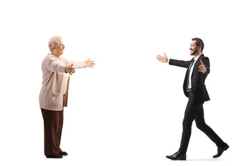 Wall Mural - Full length profile shot of a businessman walking towards an elderly woman with arms wide open