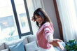 © nenetus - Pretty young woman listening to music while dancing in the living room at home.