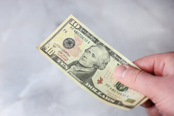 10 American dollar bill in hand on a light background