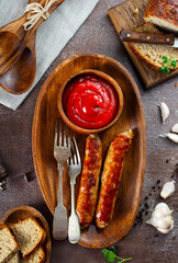 Poster - Fried sausages with sauces and herbs on a wooden serving Board. Great beer snack on a dark background. Top view with copy space