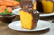 © CassianoCorreia - Close up piece of Brazilian carrot cake with chocolate frosting on wooden table with carrots in the background