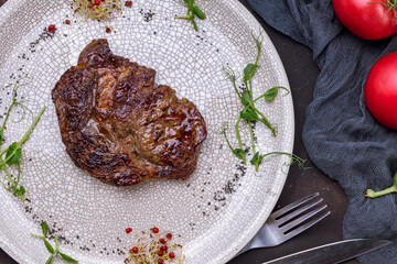 Sticker - juicy Ribeye steak on grey plate on dark stone table top view