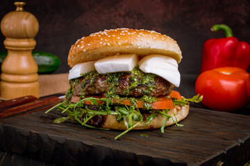 Wall Mural - Burger caprese with meat patty,  mozzarella cheese and tomatoes with aragula on dark board