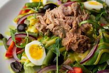 French Salad Nicoise With Tuna, Egg, Green Beans, Tomatoes, Olives, Lettuce, Onions And Anchovies On A White Background. Healthy Food