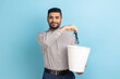 © khosrork - Portrait of smiling happy satisfied businessman throwing out his optical glasses after vision treatment, looking at camera, wearing striped shirt. Indoor studio shot isolated on blue background.
