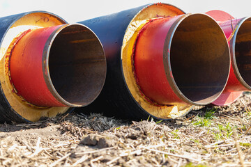 Wall Mural - Insulated pipe. Large metal pipes with a plastic sheath at a construction site. Modern pipeline for supplying hot water and heating to a residential area. Close-up.