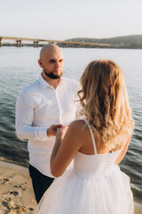 Wall Mural - Wedding photosession at sunset of a beautiful couple, the bride in a white dress, and the groom in a white shirt and black trousers