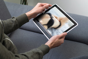 closeup of a young caucasian man watching a nude woman in his tablet computer