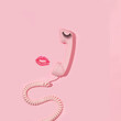 Valentines day creative layout with pink retro phone handset, false eyelash and kiss print on pastel pink background. 80s or 90s retro fashion aesthetic telephone and kiss concept. 