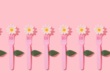 Spring creative pattern with pastel pink fork, white flower heads and leaves on pastel pink background. 80s or 90s aesthetic fashion food restaurant concept. Minimal romantic summer idea.