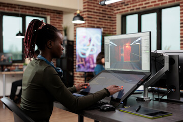 Wall Mural - Electronic arts company employee working on 3D project while modeling environment. African american developer sitting in creative agency office workspace while designing game level.