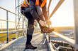 © Dusan Petkovic - A heavy industry worker tying shoelace on his work shoes while standing on height.