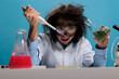 Foolish silly female lab worker with pipette and glass jar mixing toxic chemical compounds to create new formula. Crazy mad scientist mixing liquid substances while grinning dreadful.