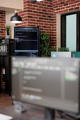 interior of empty data center office with multiple computer screens showing programming line codes. 