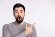 © Tetiana - Photo of young guy amazed shock omg reaction indicate finger empty space advertisement isolated over grey color background