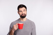 © Tetiana - Photo of wondered guy look empty space dream drink hot americano minded isolated on grey color background