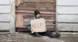 Homeless man sits and holds piece of cardboard with inscription Help. Refugee looking for job. Male tramp in dirty clothes, hat cap. Below poverty line. Bearded fugitive beggar. Immigrant. Drunkenness