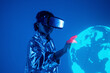 © VISTA by Westend61 - Woman wearing virtual reality simulator touching earth on screen against blue background