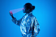 © VISTA by Westend61 - Woman wearing smart glasses scanning futuristic smart phone against blue background