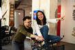 © JustLife - Colleagues in office. Businesswoman and businessman with bicycle. Two friends having fun together