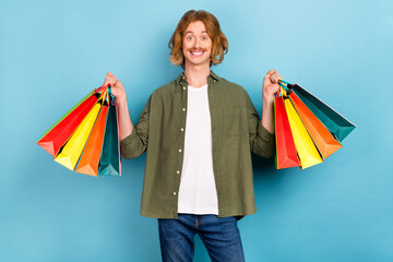 Sticker - Portrait of attractive funky cheerful guy holding in hands new things buyings outlet isolated over pastel blue color background