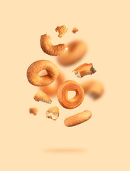 Wall Mural - Creative food, baking layout. Fresh round wheat bagel with sesame seeds flying on beige background. Crispy bread, healthy organic food, traditional pastries, bakery product. Breakfast bagel