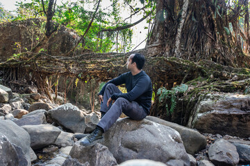 young man with isolated tree root bridge natural formed single decker at day from flat angle