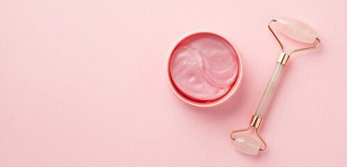 Wall Mural - Top view photo of rose quartz roller and pink eye patches on isolated pastel pink background with copyspace