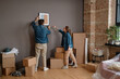 © Mediaphotos - Horizontal long shot of young Caucasian man and woman choosing wall in new apartment to hang paintings on