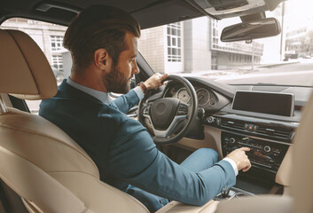 Adorable bearded man in suit is going to the business journey while turning on audio