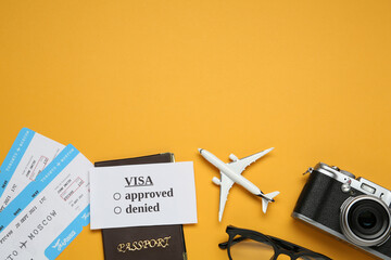 Canvas Print - Flat lay composition with passport, toy plane and camera on orange background, space for text. Visa receiving