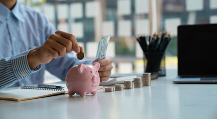 Wall Mural - Businessman with a coin in a piggy bank along with pressing the calculator and writing down savings for the future after retirement, ideas for saving money for the future and life after retirement