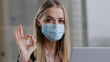 Portrait caucasian masked girl female student businesswoman user in medical protective face mask health insurance shows ok gesture good feeling recovery consent agree symbol everything fine great sign