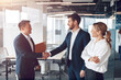 © Yaroslav Astakhov - Welcome to our team, mature modern men in formal wear shaking hands in modern office.