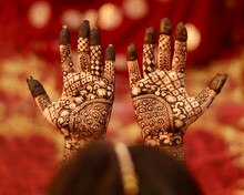 Closeup Of Female Hands With Indian Henna Tattoos (mehndi) Against Blurry Red Background