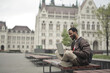 © olly - young man sitting on a bench uses a computer