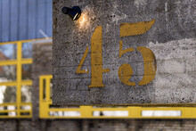 Closeup Shot Of Yellow Number Forty Five On Concrete Wall