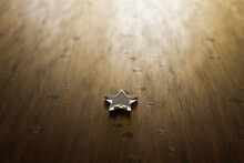 One Star Rating - One Transparent Acrylic Glas Star Lying On A Wooden Table. Selective Focus And Copy Space.