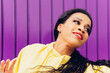© Dani D.G - Portrait of happy pretty woman of African ethnicity in motion, dancing outdoors on purple background. Concept of music, urban dance, hip hop, trap.