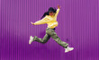© Dani D.G - Jumping young woman in yellow dress on purple background. Dancer of hip hop and trap music. Concept of freedom, celebration, joy.