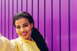 © Dani D.G - Young influencer taking a selfie portrait on a purple background. Happy girl in yellow clothes and urban style.