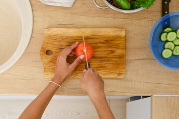 View from above at hands of african american woman cutting tomato for salad