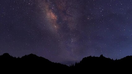 Night time lapse. Starry night background. The Milky Way Galaxy moving over the mountain ridge
