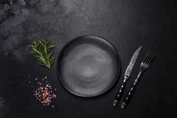 Empty round black plate on dark moody black background with copy space