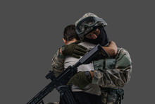 Portrait Of Professional Serviceman Dressed In Camouflage Clothes Hugging Little Boy.
