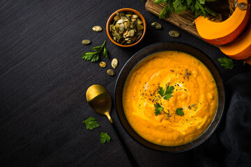 Wall Mural - Pumpkin soup puree with ginger and cream. Top view image at black stone table.