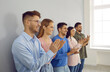© Studio Romantic - Group of happy joyful young people applaud at business conference or team meeting. Side view of smiling modern business men and women standing in row near wall and applauding their leader.